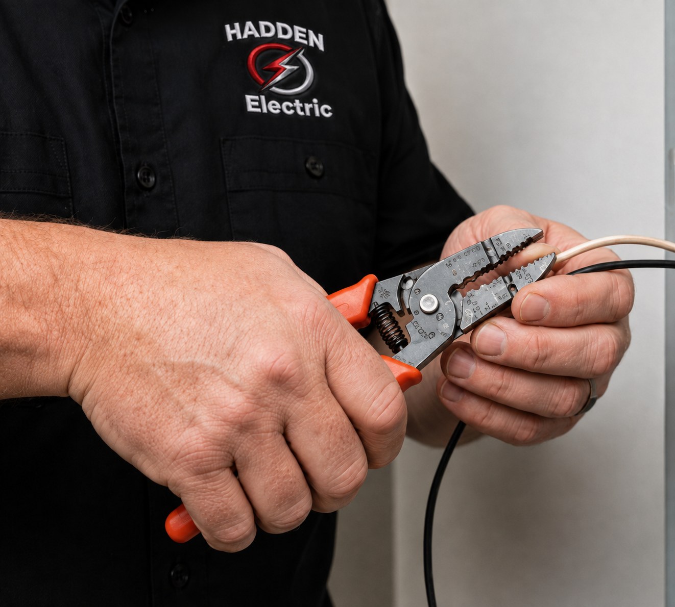 Close-up of an electrician's hands stripping residential wiring with wire strippers