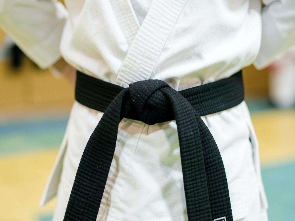 Close-up of a black belt tied over a white gi